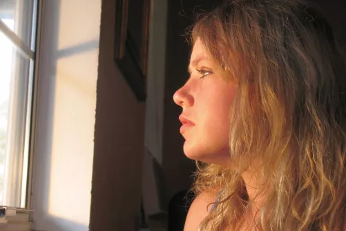 Ablakon kedvetlenül kinéző nő