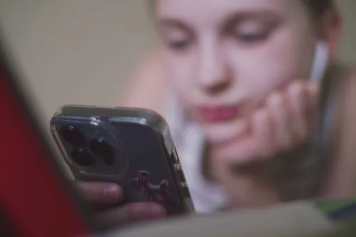 Iskolás a mobilját nézi