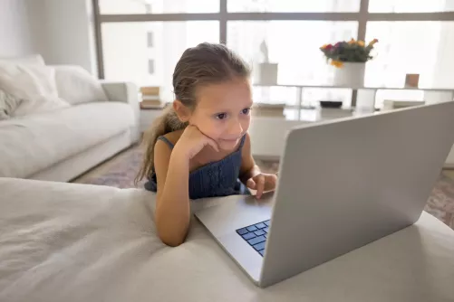 Kislány notebook képernyőjét nézi