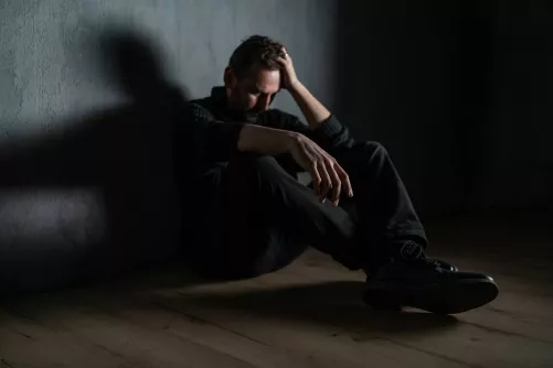 Férfi gubbaszt a sötétben