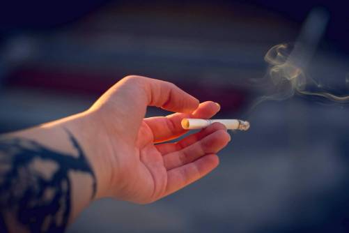 Füstölgő cigaretta a kézben (illusztráció)