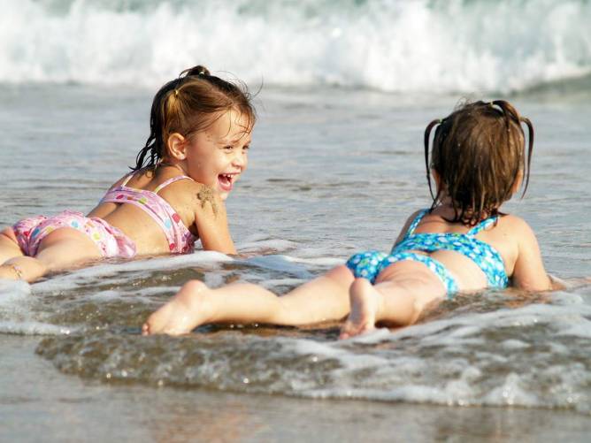 Pancsoló, napfürdőző gyerekek a tengerparton