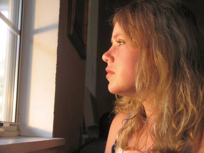 Ablakon kedvetlenül kinéző nő