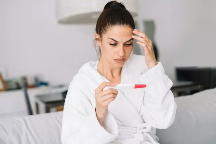 Terhességi teszt eredményével szembesülő nő
