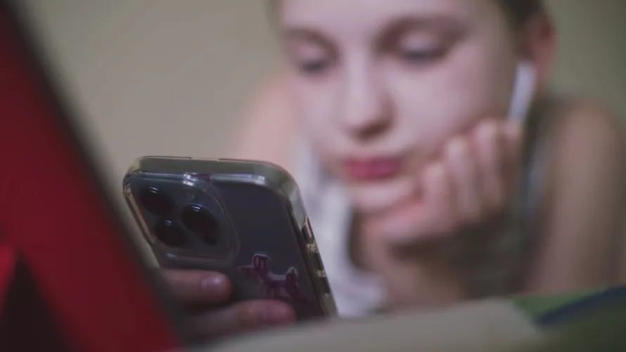 Iskolás a mobilját nézi