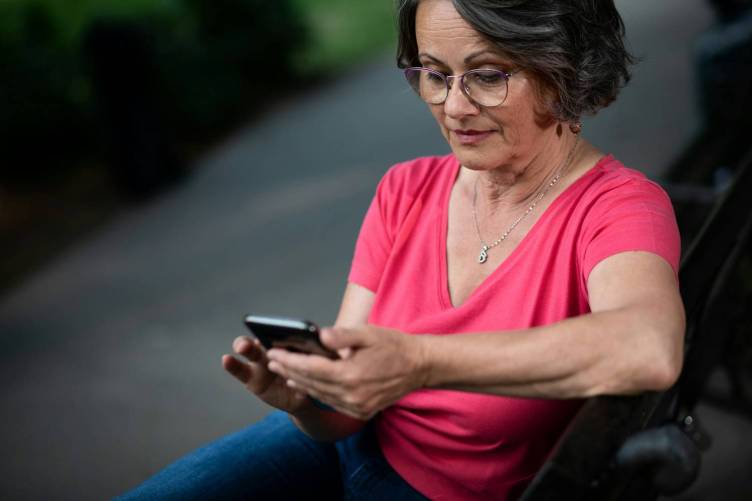 Mobiltelefonján böngésző nő