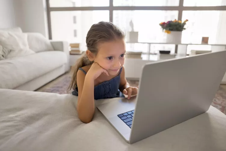 Kislány notebook képernyőjét nézi