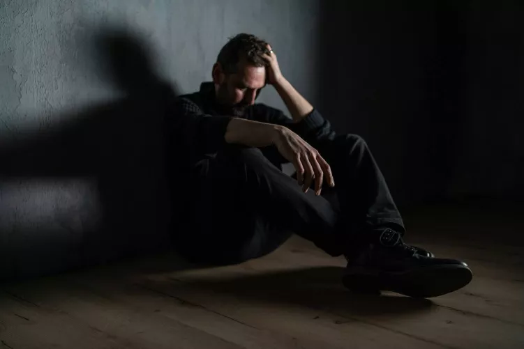 Férfi gubbaszt a sötétben