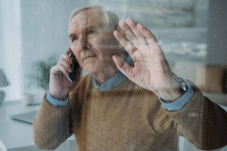 Magányos idősebb úr az ablakban.