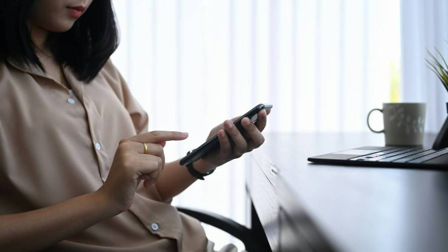 Mobiltelefonját használó nő