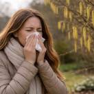 Allergiás nő mogyoróbokorral a háttérben.